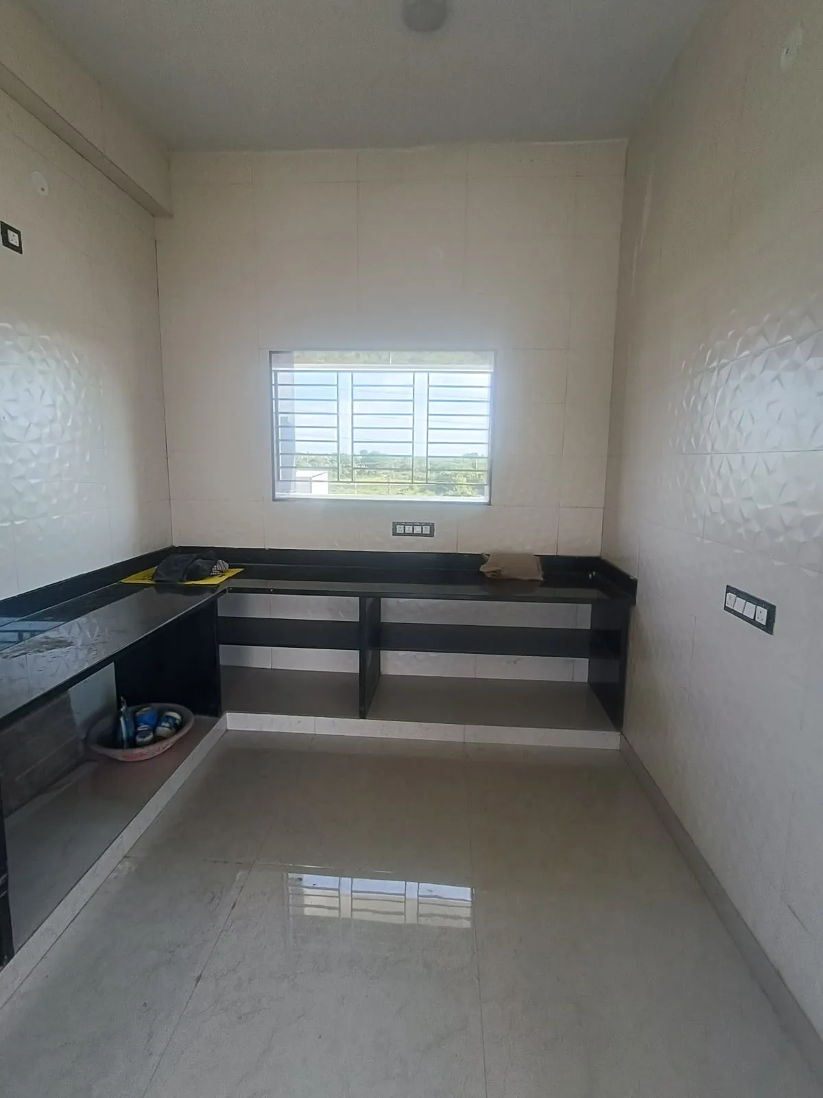 The Swamy residence kitchen before: an open black granite counter platform with no shutters and bare tiled walls